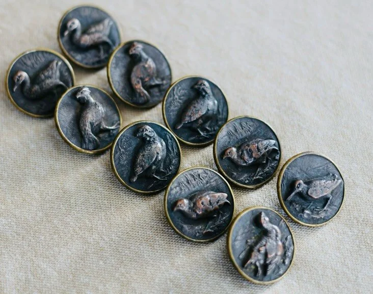 Ten two-piece brass buttons with Paris backs &mdash; beautifully embossed, each adorned with a game bird. Every plume and feather is thoughtfully rendered in rich brass relief, showcasing detail and craftsmanship.

Often considered French hunting or 