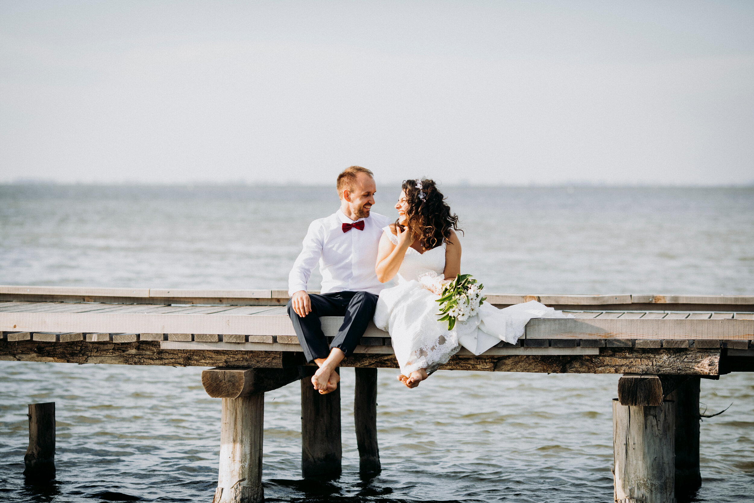 Bride and Groom Sitting on Wooden Dock.jpg