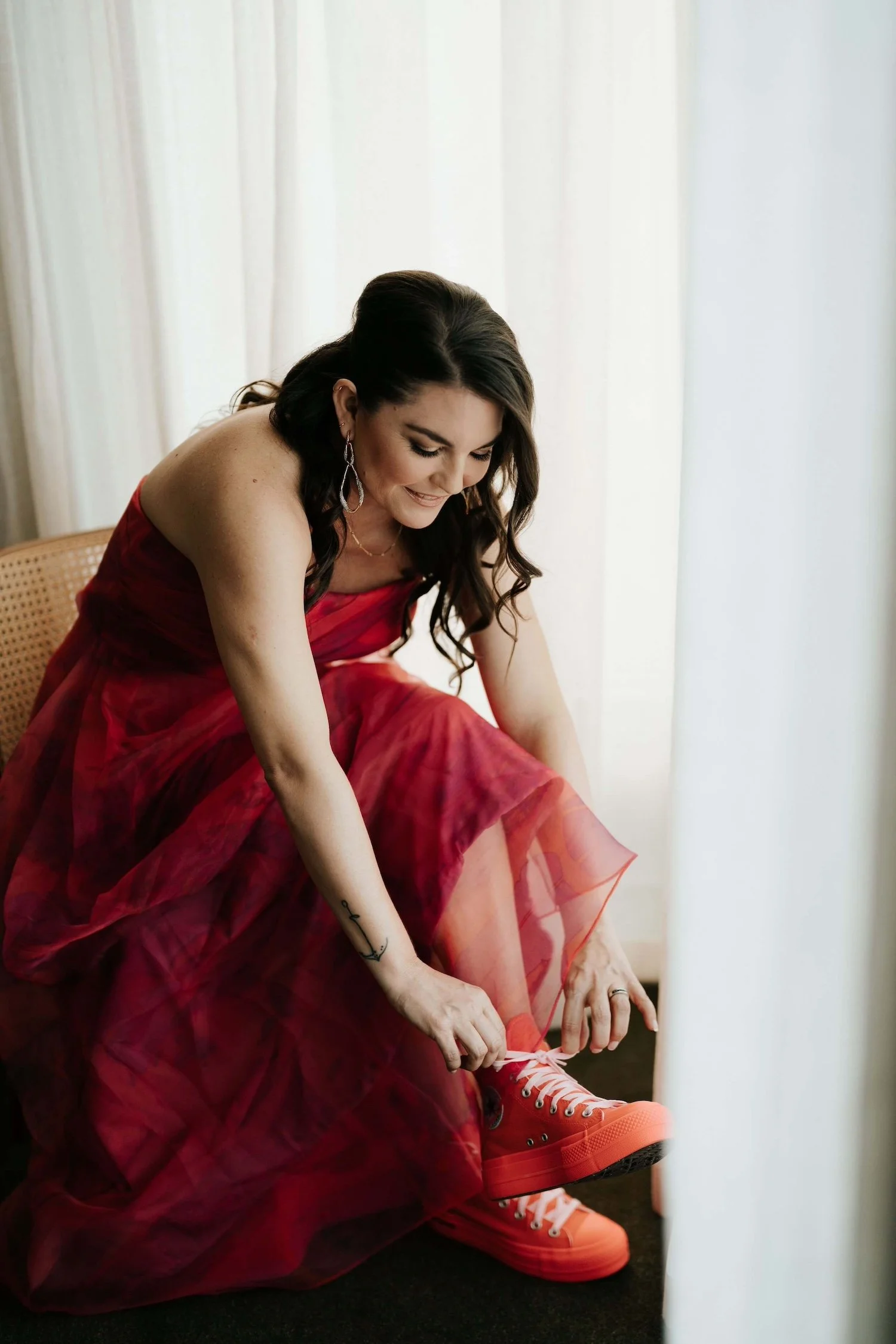Bride in fuchsia dress tying her Converse shoes