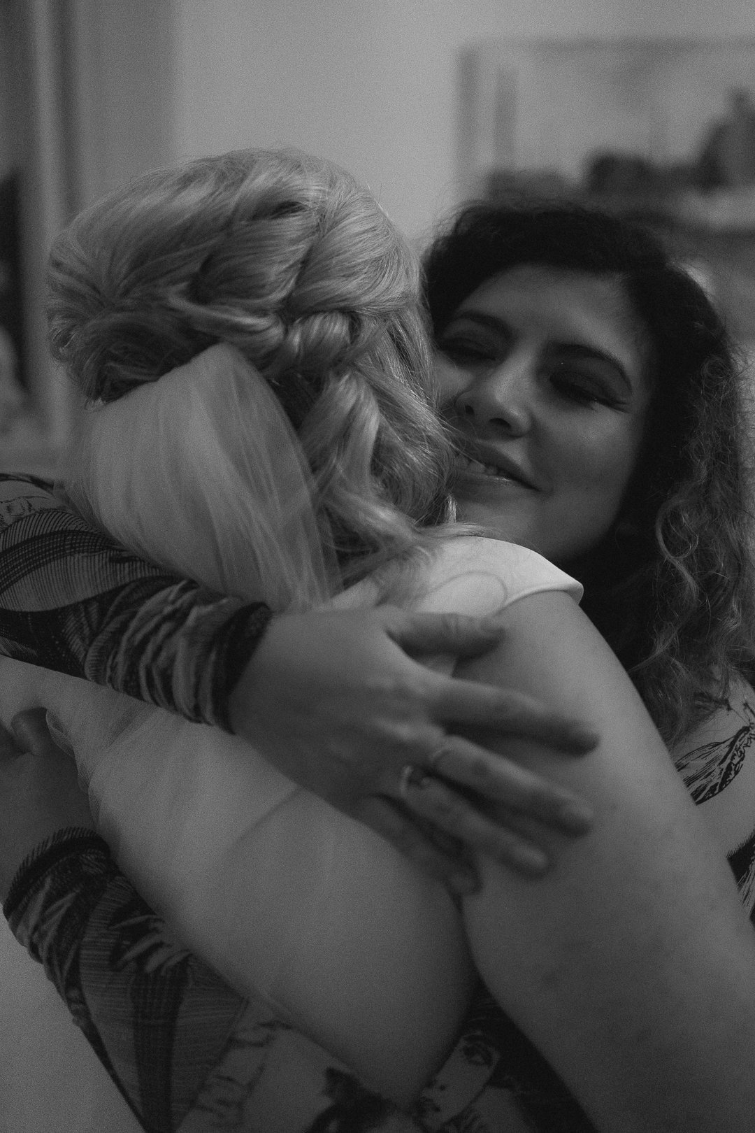 Daughter-in-law hugging the bride with beautiful half-up hair
