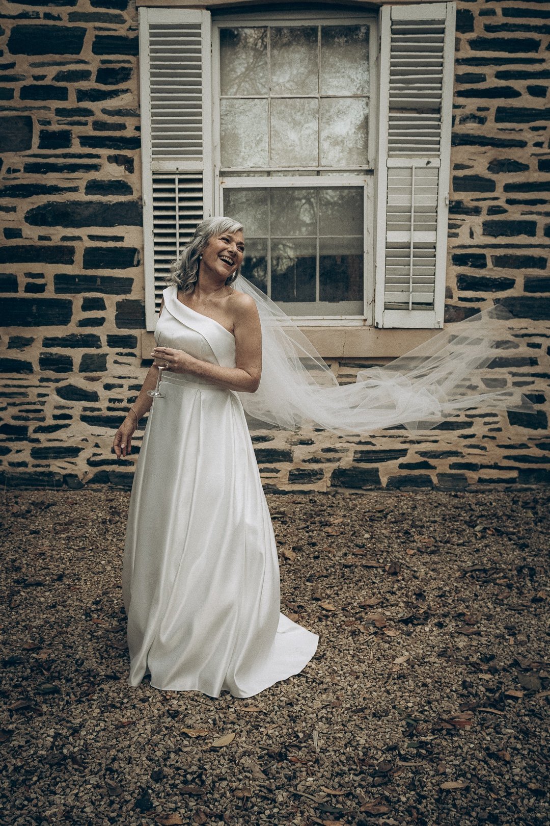 Bride smiling as her veil gently flows in the winter breeze