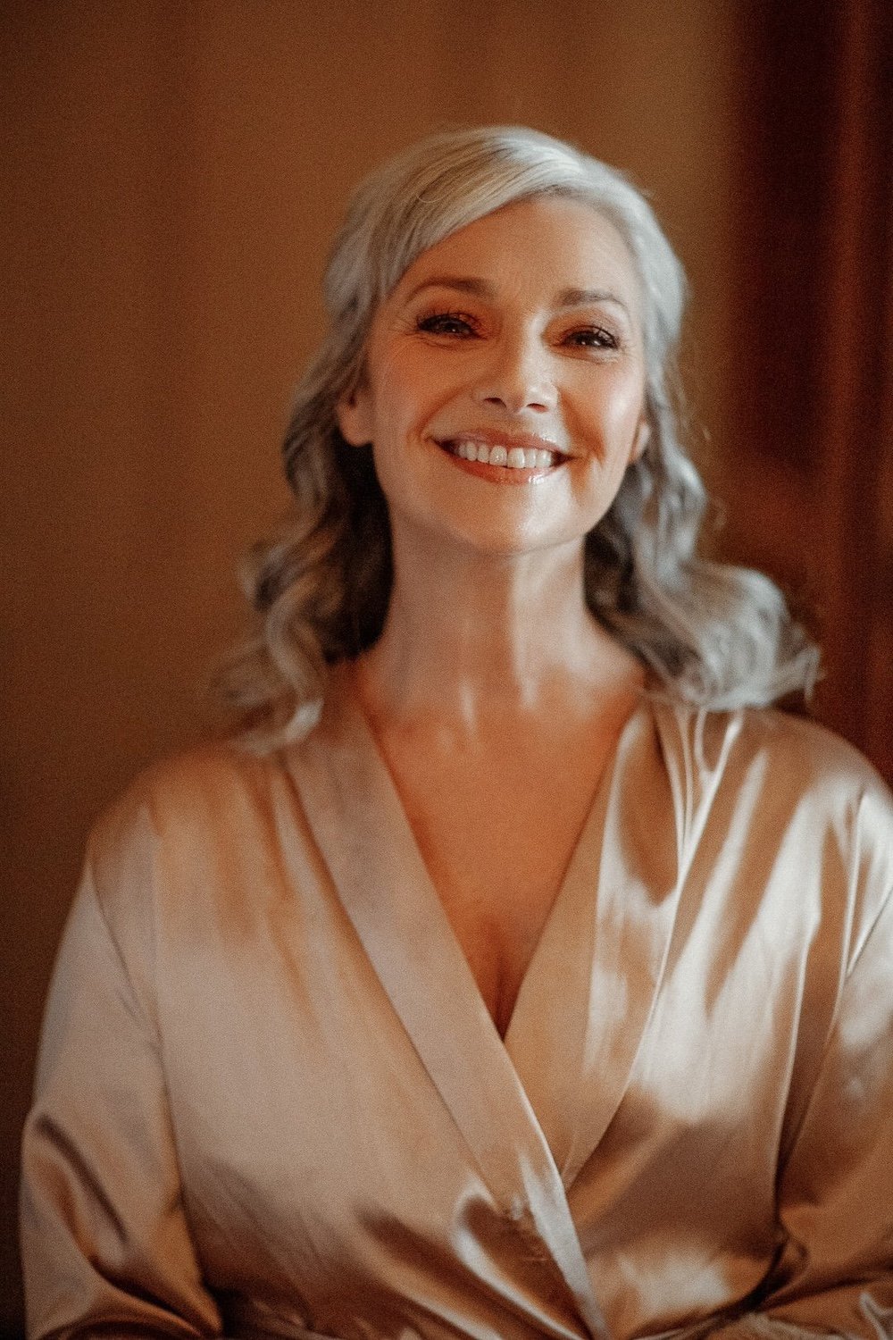 Smiling bride getting hair and makeup done