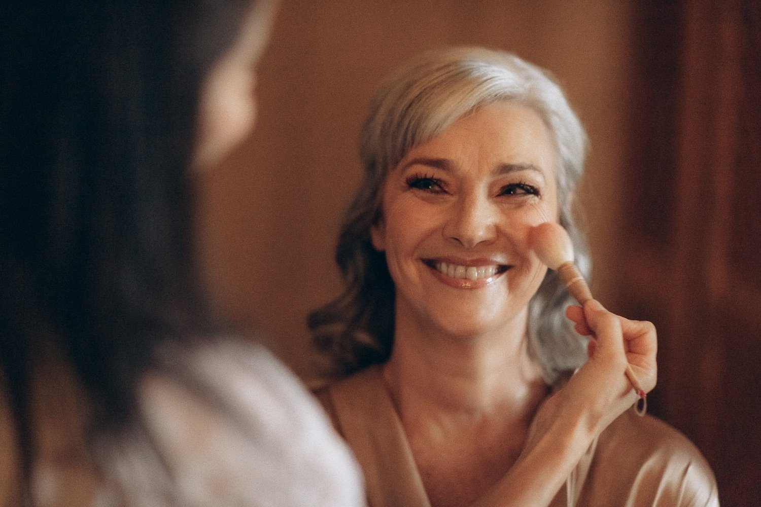 Bride smiling as Pia Bedregal perfects her makeup and hair