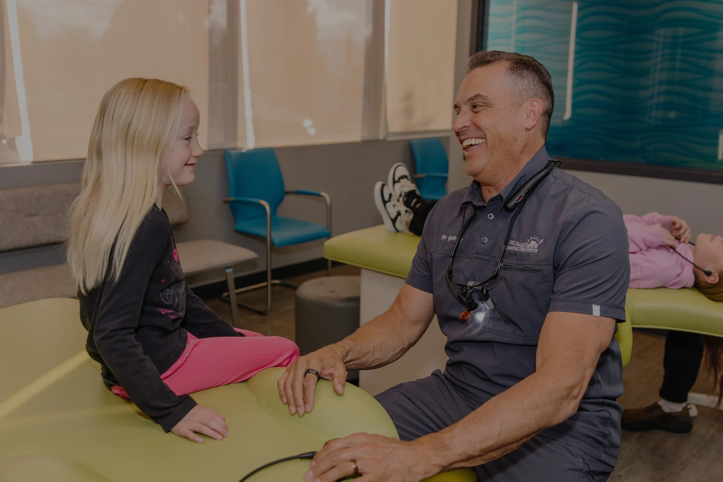 Pediatric Dentist Dr. Gehring at office smiling and laughing with young girl patient