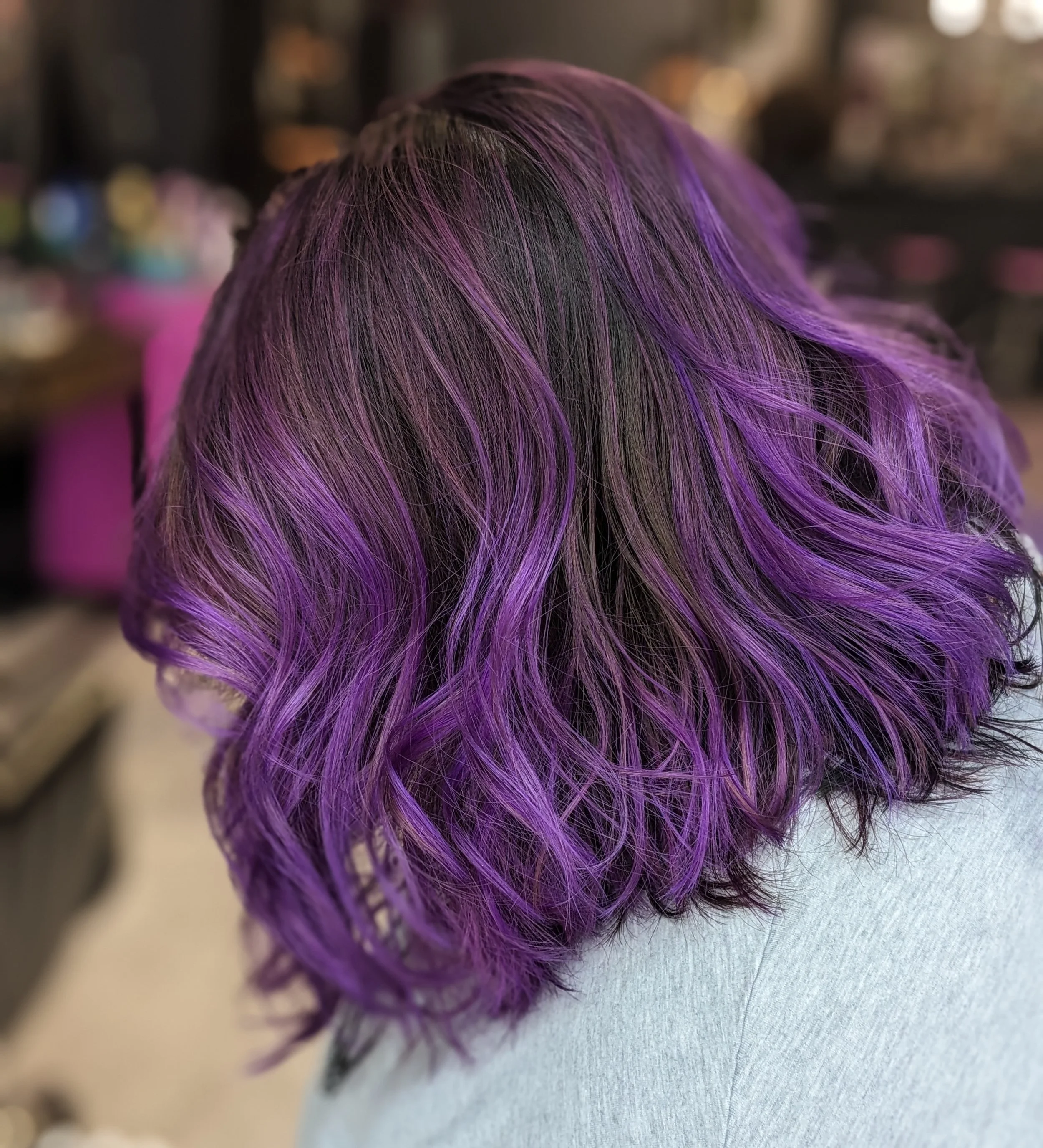 Woman with wavy hair dyed in shades of purple and black.