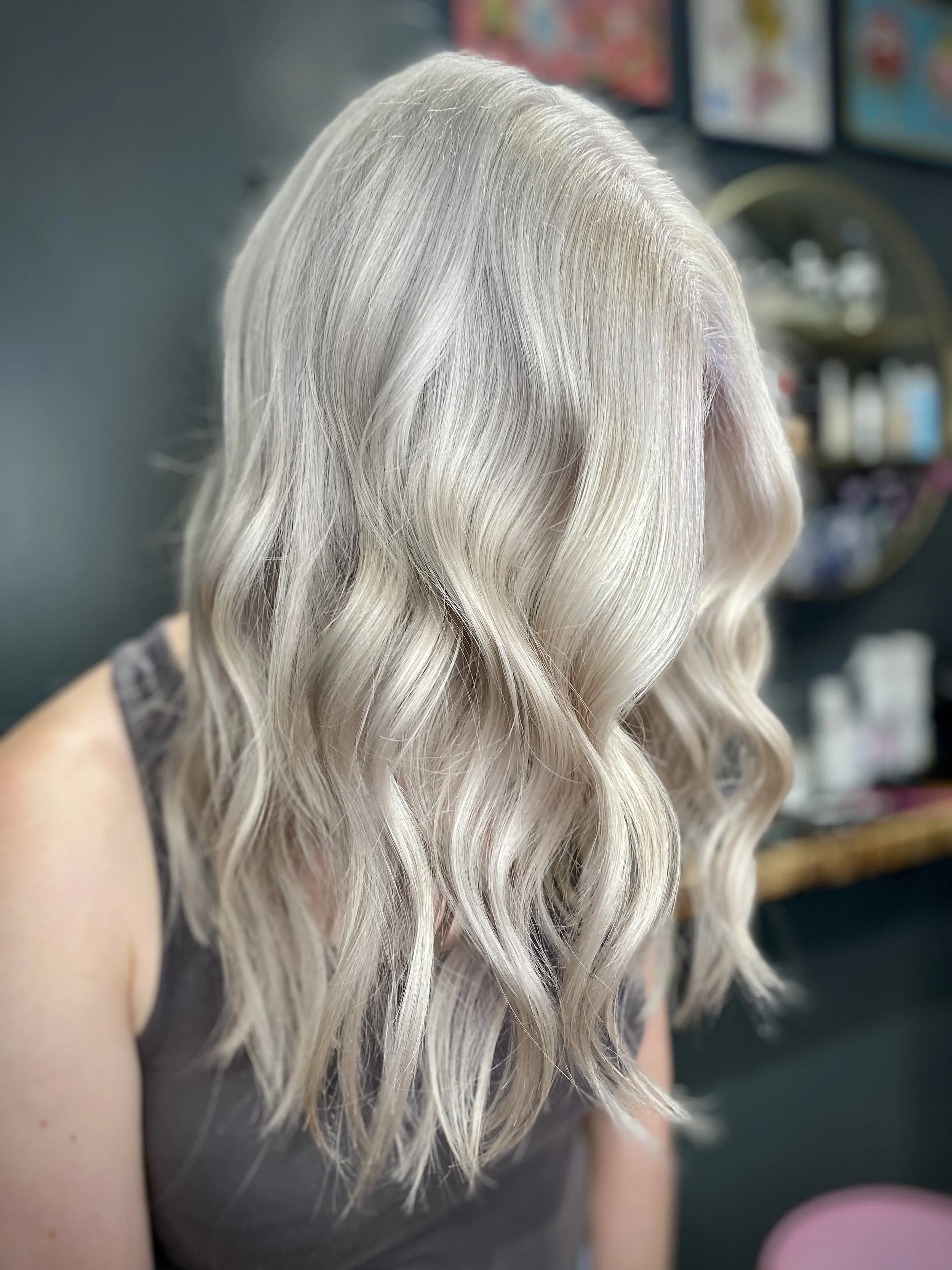 Side view of a woman with shoulder-length, wavy, platinum blonde hair.