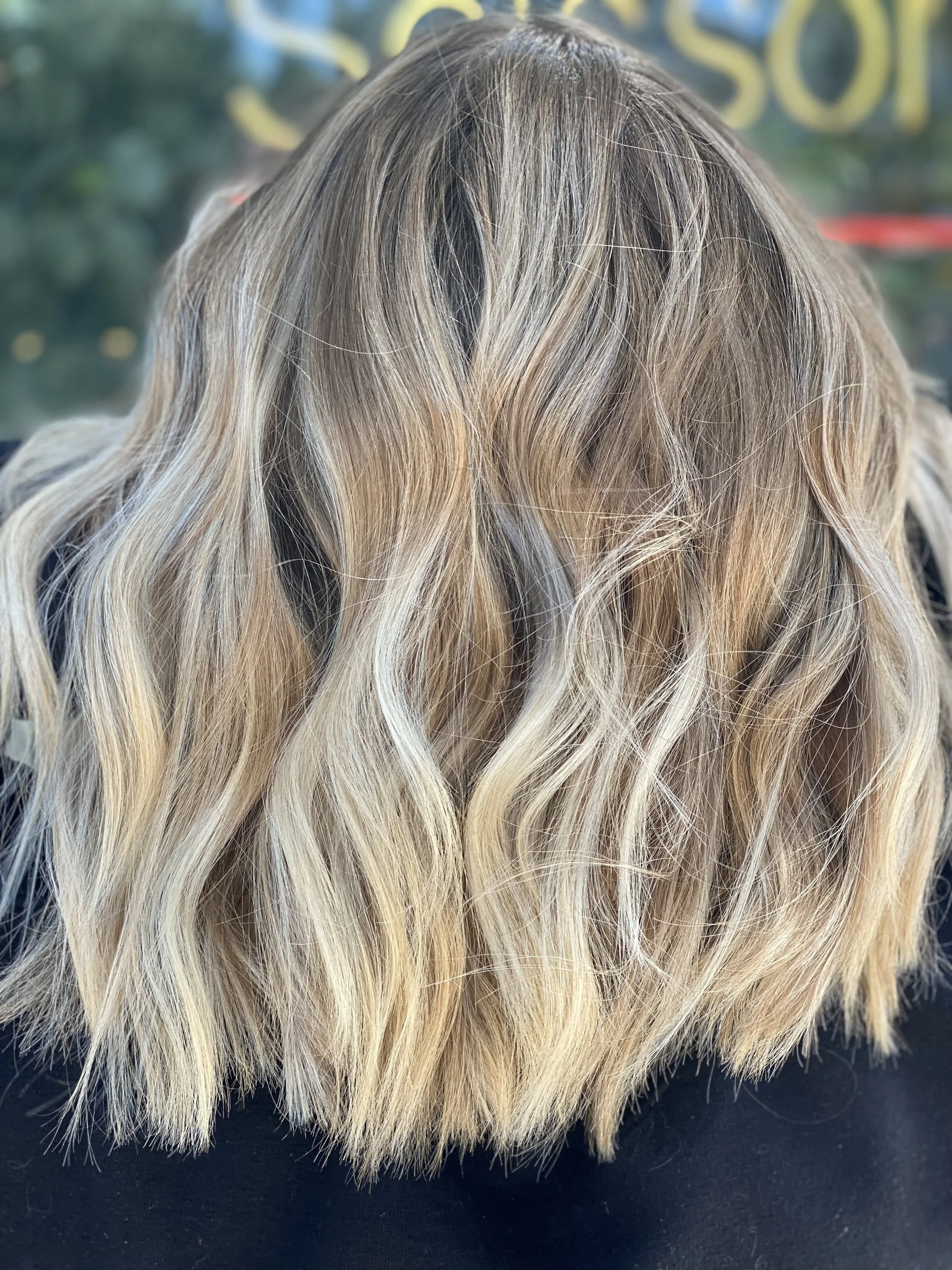 A close-up view of wavy blonde hair with darker roots.