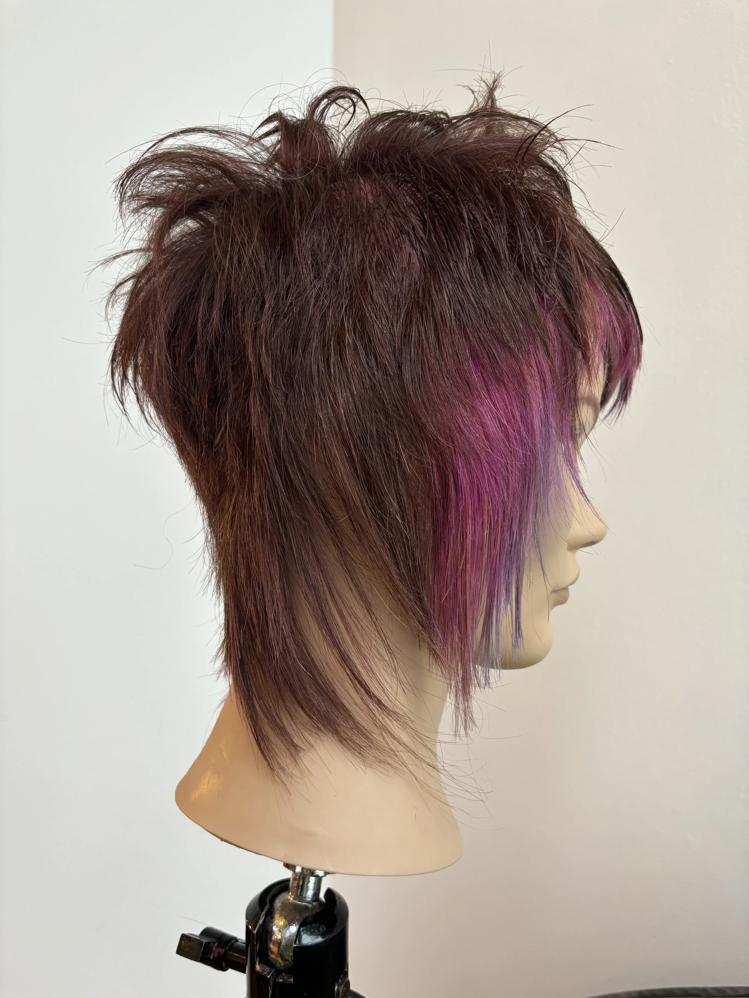 Short layered asymmetrical hairstyle on a mannequin with brown and pink hair.