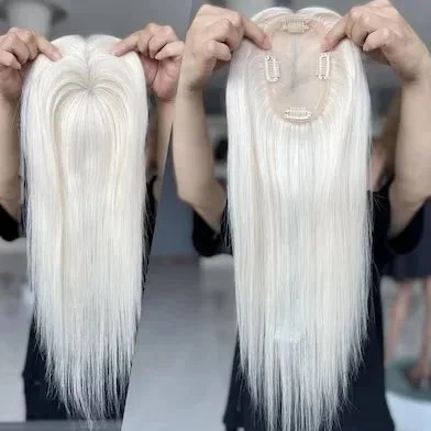 A person holding platinum blonde hair extensions attached to a hair wig cap.
