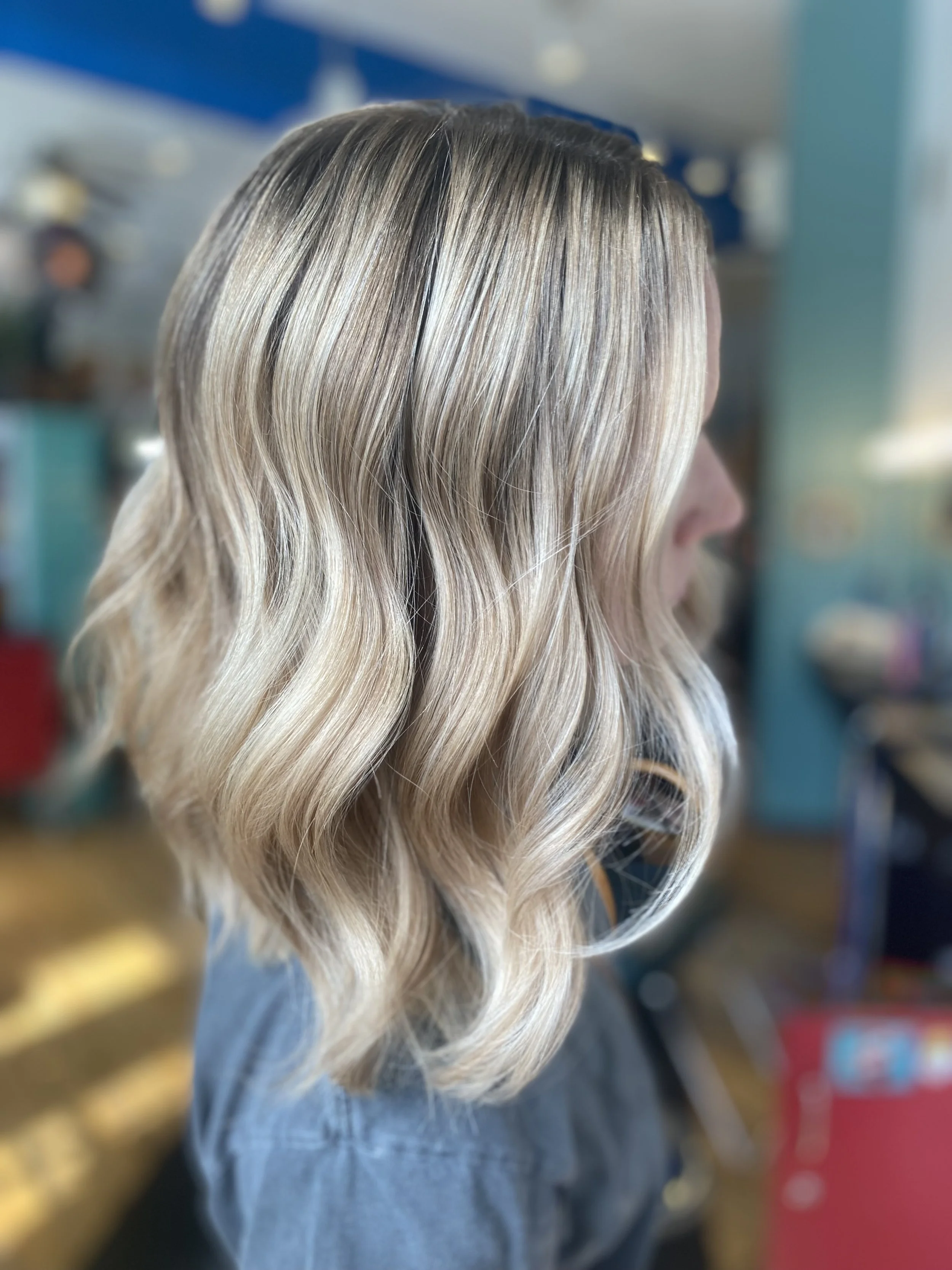 Side view of a woman with wavy blonde hair in a salon.