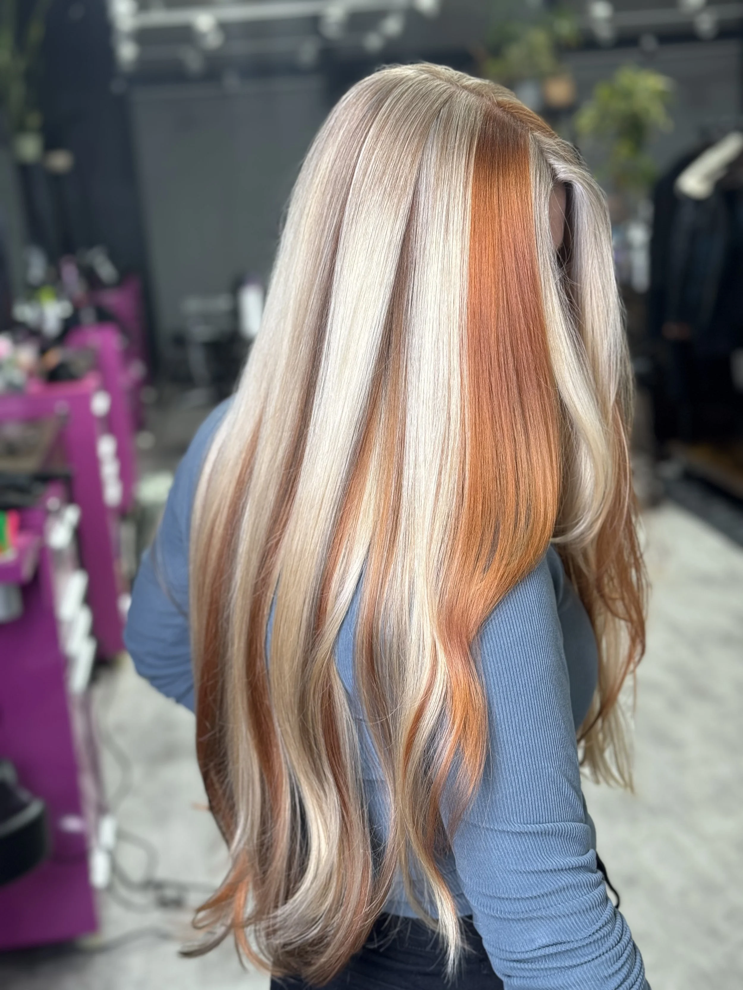 Long blonde hair with orange and peach highlights, styled in loose waves.