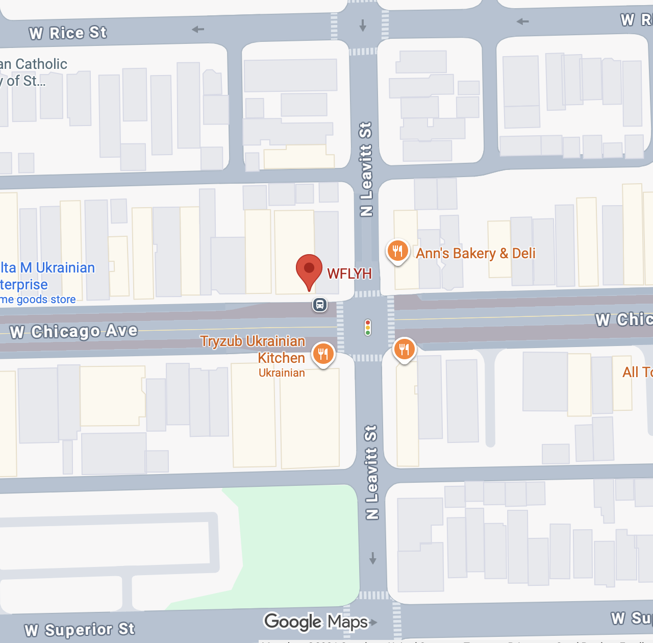 Beauty salon with three black salon chairs, pink rolling carts, mirrors, and a black wall with potted plants, with track lighting above.