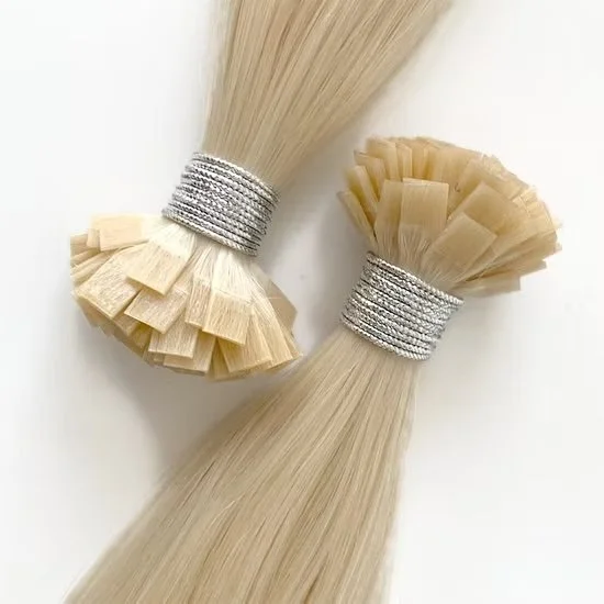 Two bundles of light blonde hair extensions secured with silver glittery hair ties, arranged on a white surface.