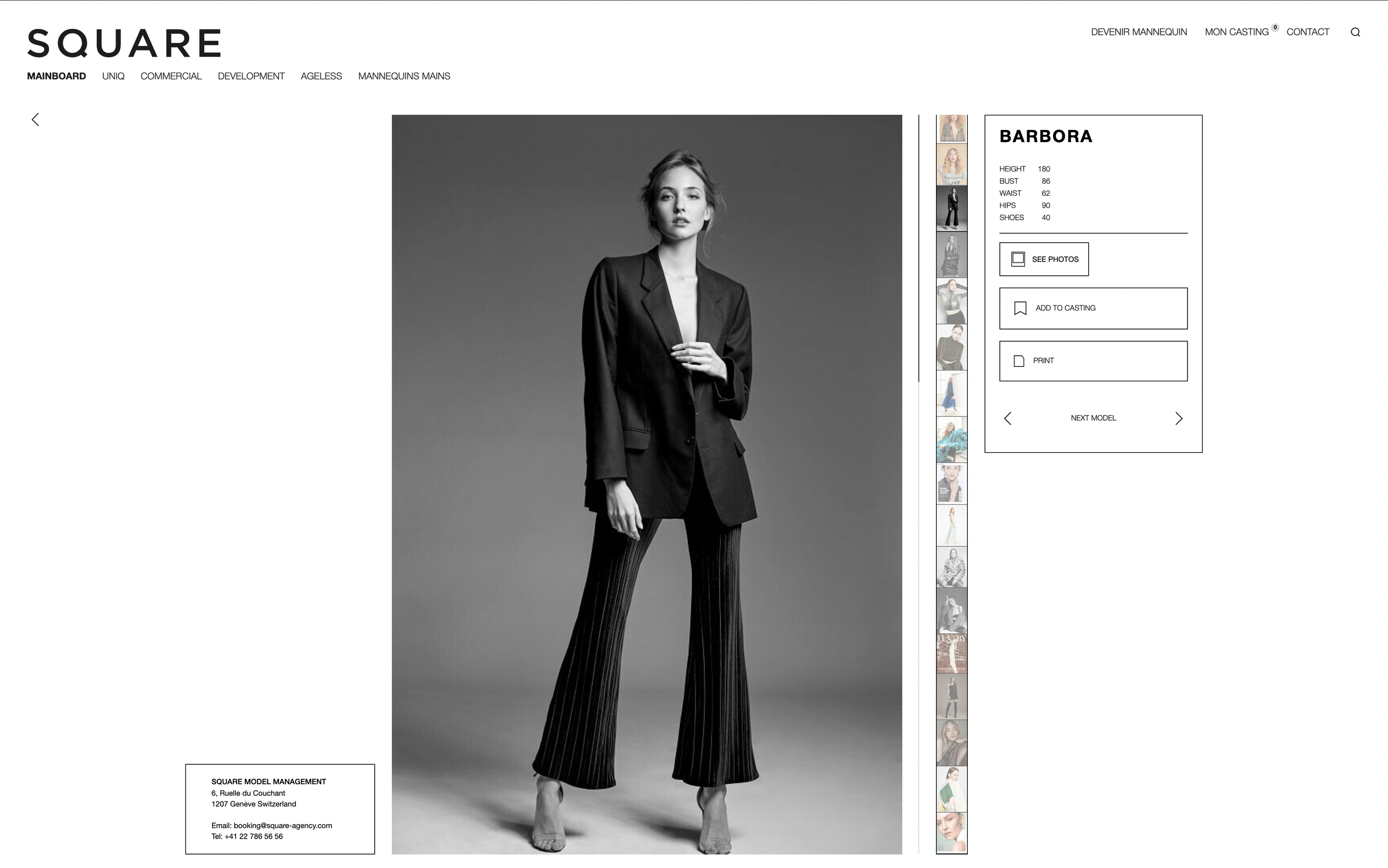 Modèle féminin en noir et blanc portant un blazer avec des pantalons à rayures, posé contre un fond gris.