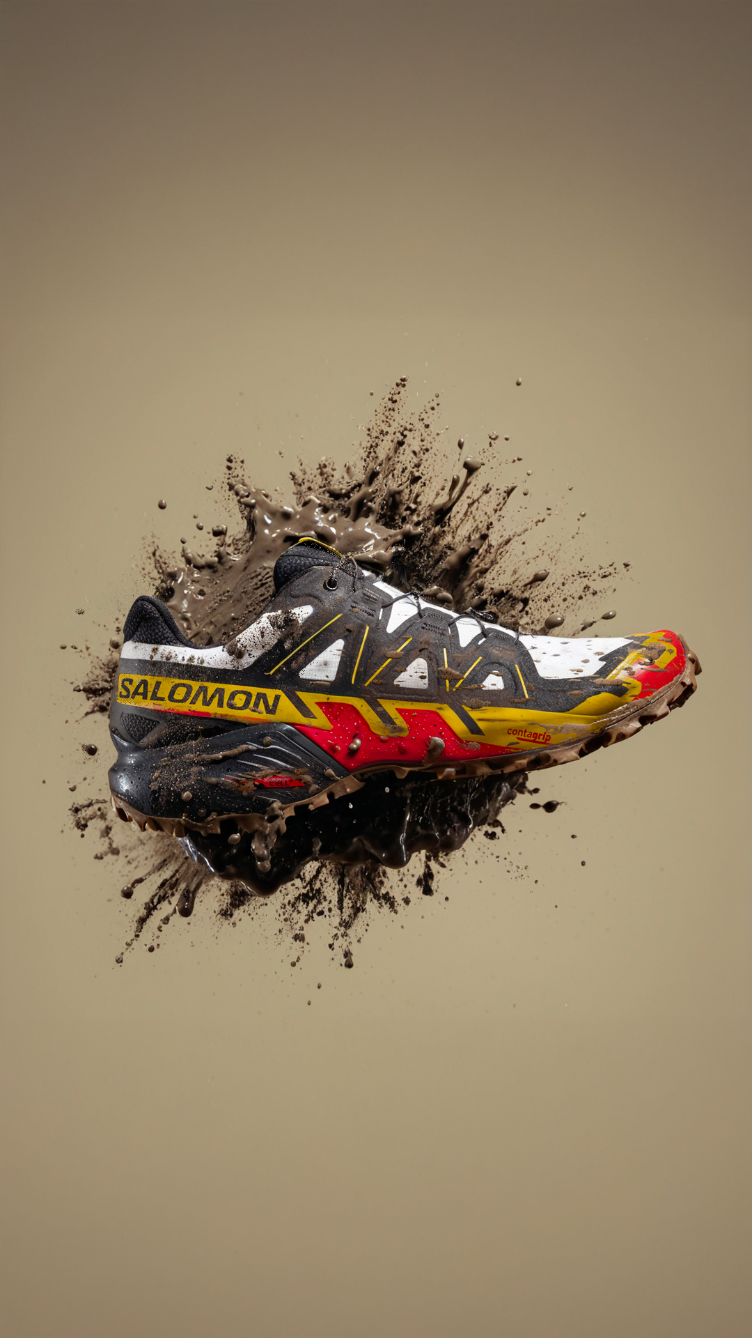 A Salomon running shoe surrounded by splashes of mud or dirt.
