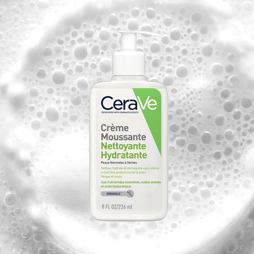 Une bouteille de crème mousseuse nettoyante hydratante pour peaux normales à sèches, avec de la mousse blanche en arrière-plan.