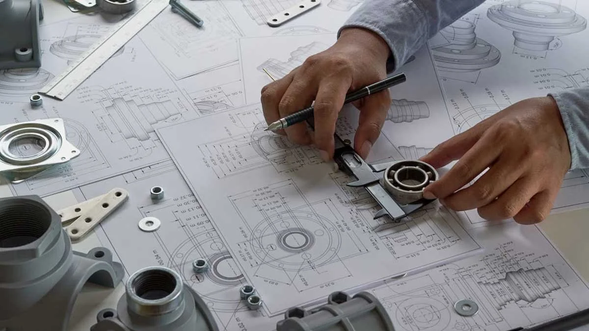 Person measuring and inspecting mechanical components on engineering blueprints with calipers and technical drawings on a table.