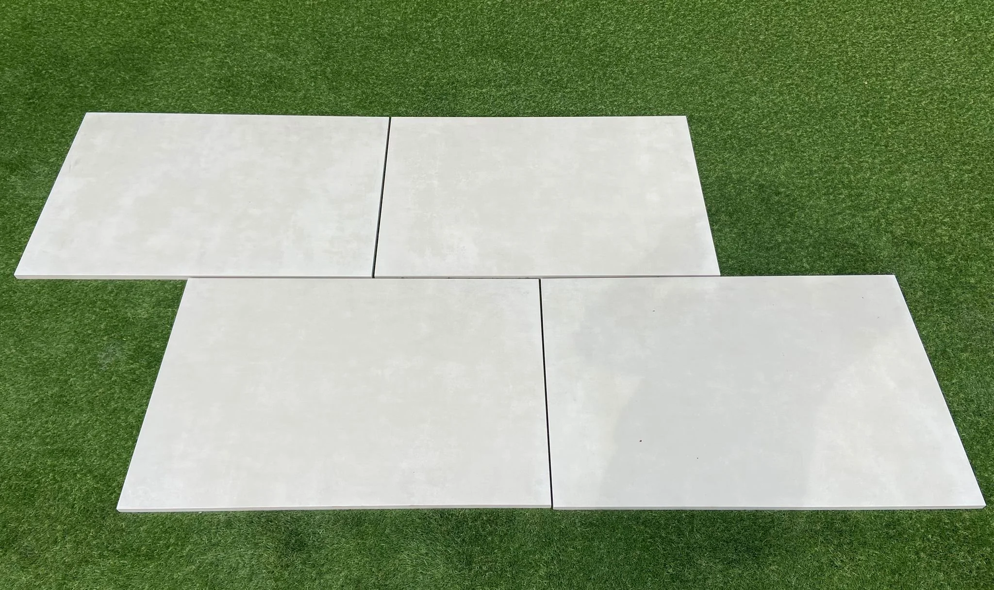Image of Portuguese Cream Porcelain slabs sitting on  grass. The slabs are a clear cream colour  