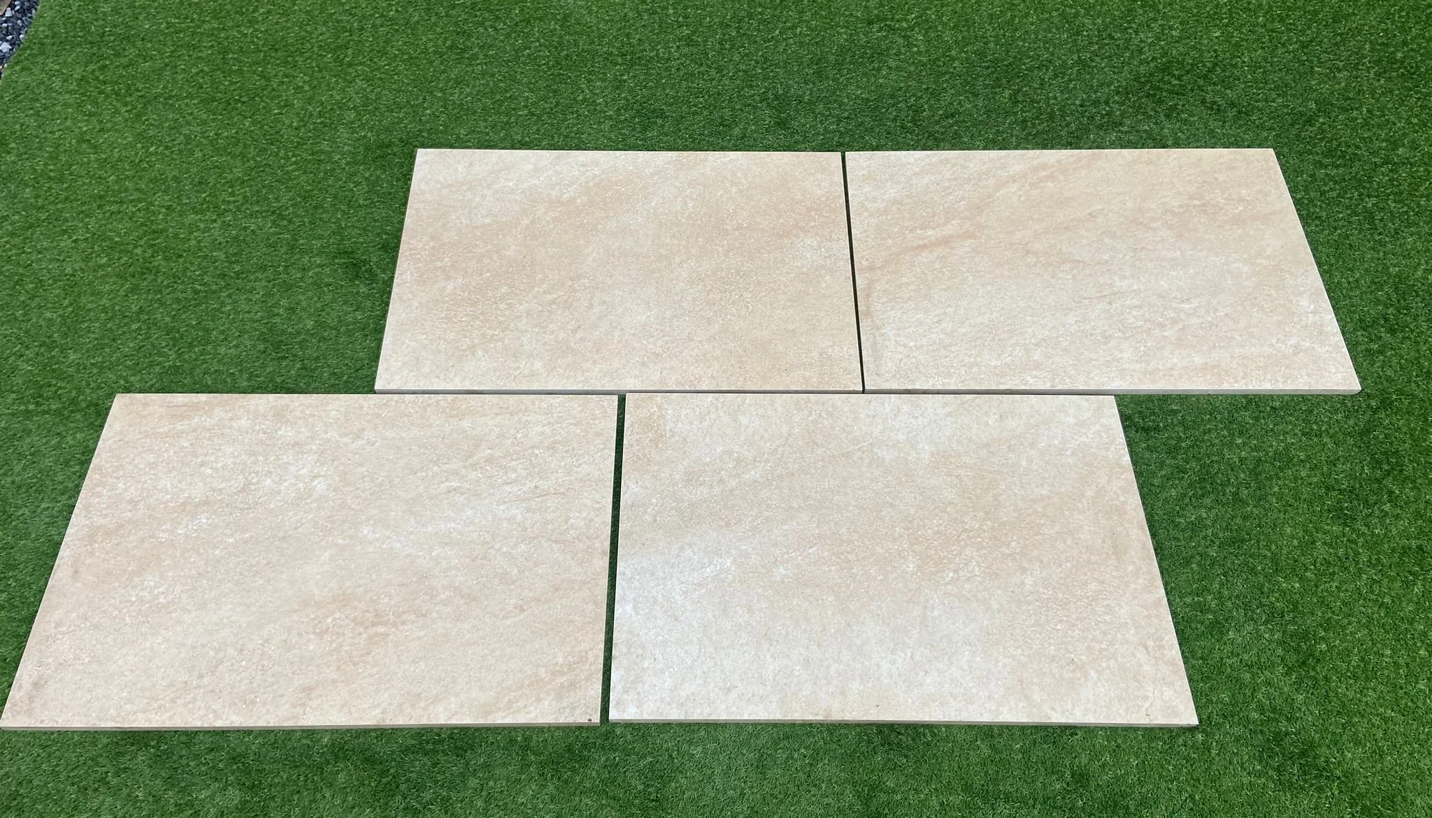 Image of 4 Beige Porcelain slabs on a grass background in Shanlieve Stones Quarry in Newry where they supply their natural stone paving from