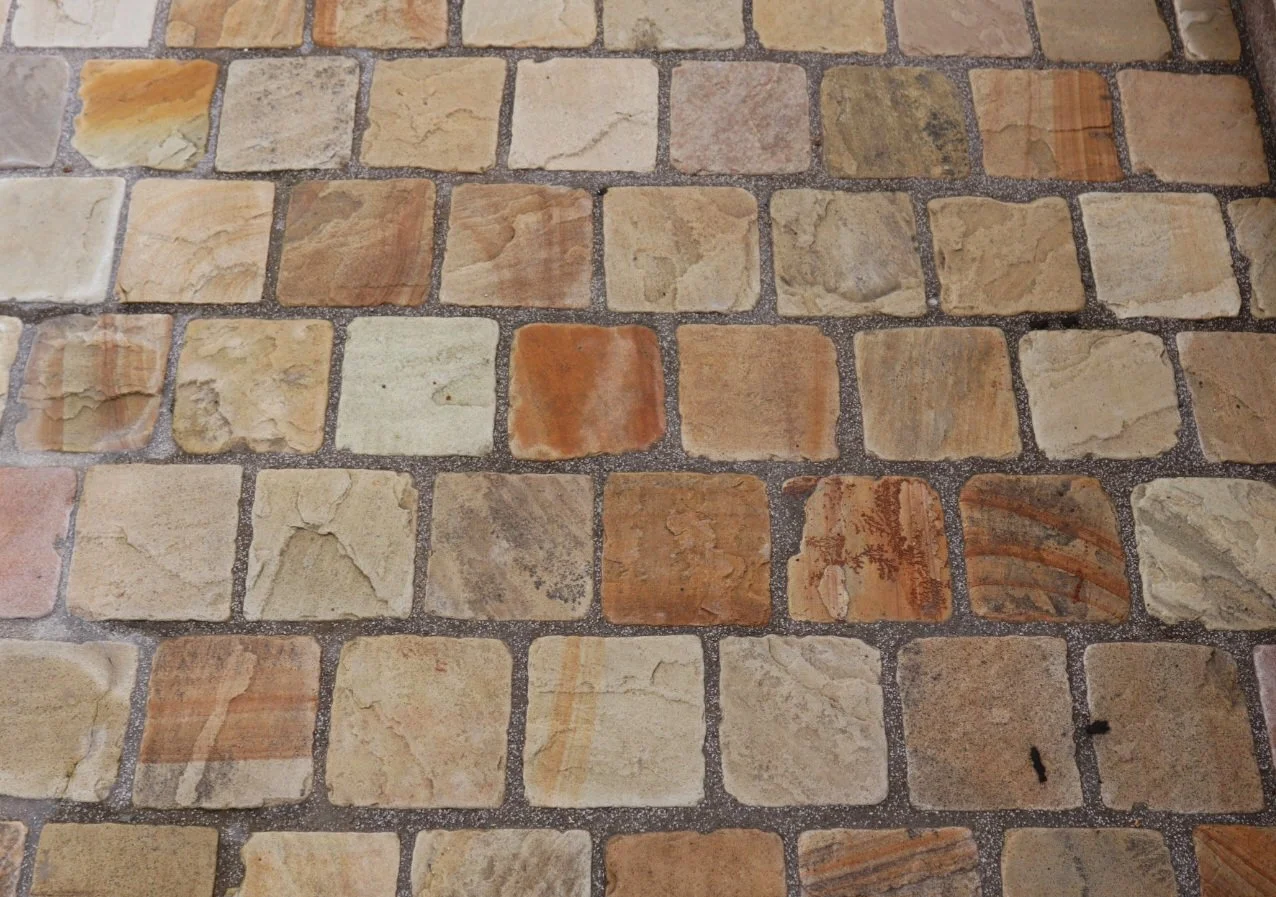 Image of an indian sandstone cobble in standard sizes laid on a natural stone cobble pathway