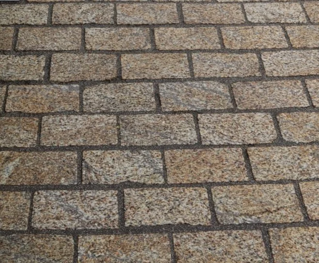 Image of a standard brown granite cobble with a straight cut edge laid in a pathway