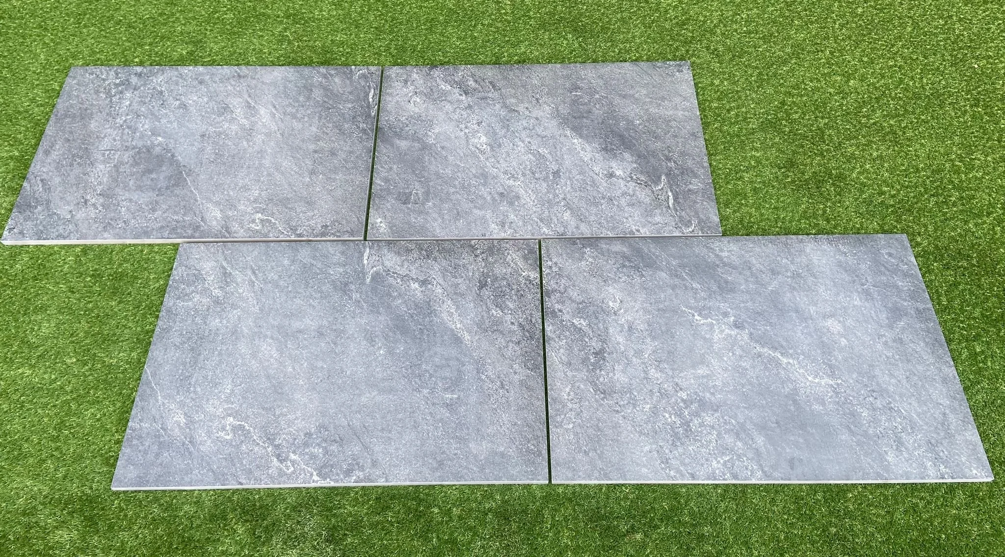 Image of black porcelain as supplied by Shanlieve Stone in their yard in Newry county down, Northern Ireland. Image is of 4 slabs sitting on the grass displaying the size and finish of the porcelain