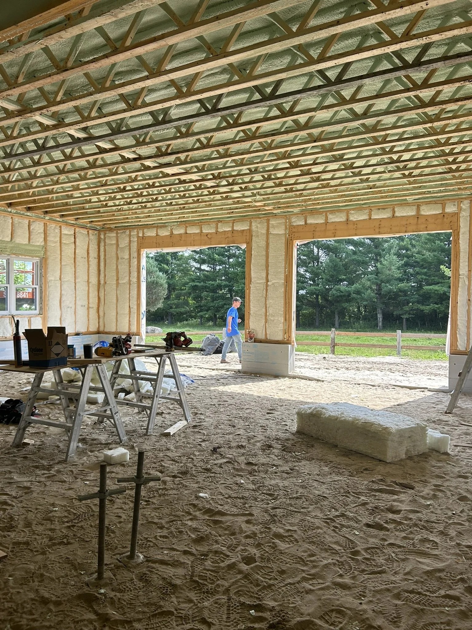 Early framing stage of century farmhouse addition above two-car garage in Quebec