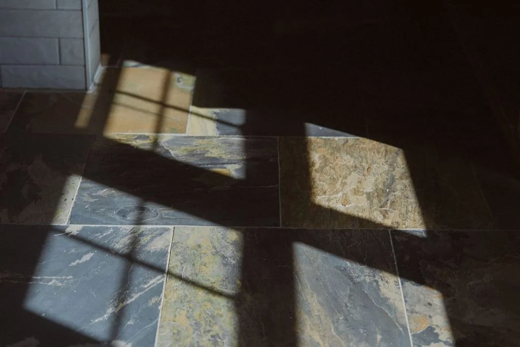 Natural slate flooring with sunlight shadows in century farmhouse bathroom renovation