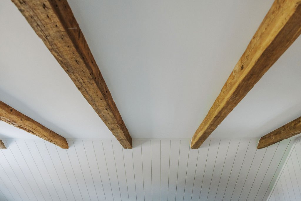 Reclaimed hemlock barn wood ceiling beams in century farmhouse addition by Anika Schachtler Design