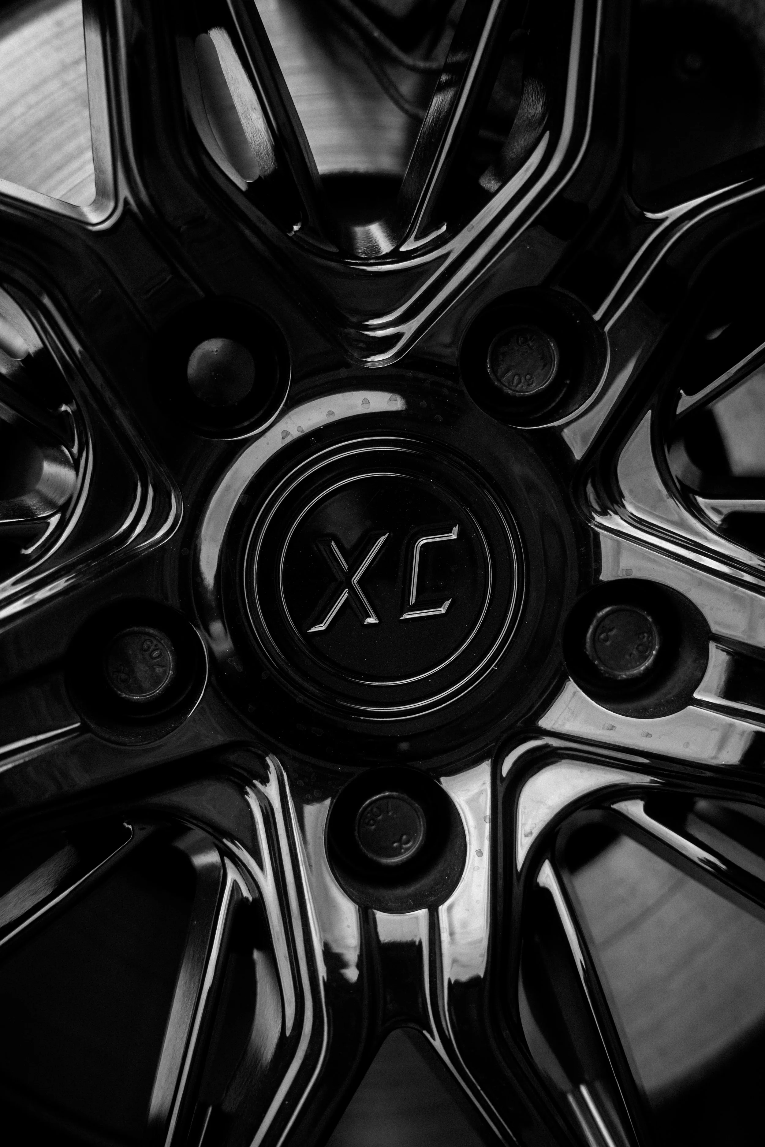 Close-up photo of a chrome alloy wheel with the center cap displaying the letters 'XC' embossed.