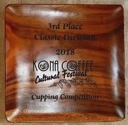 Wooden plaque with engraved text recognizing Aloha Star 100% Kona Coffee Farm third place in the 2018 Kona Coffee Cultural Festival Cupping Competition.