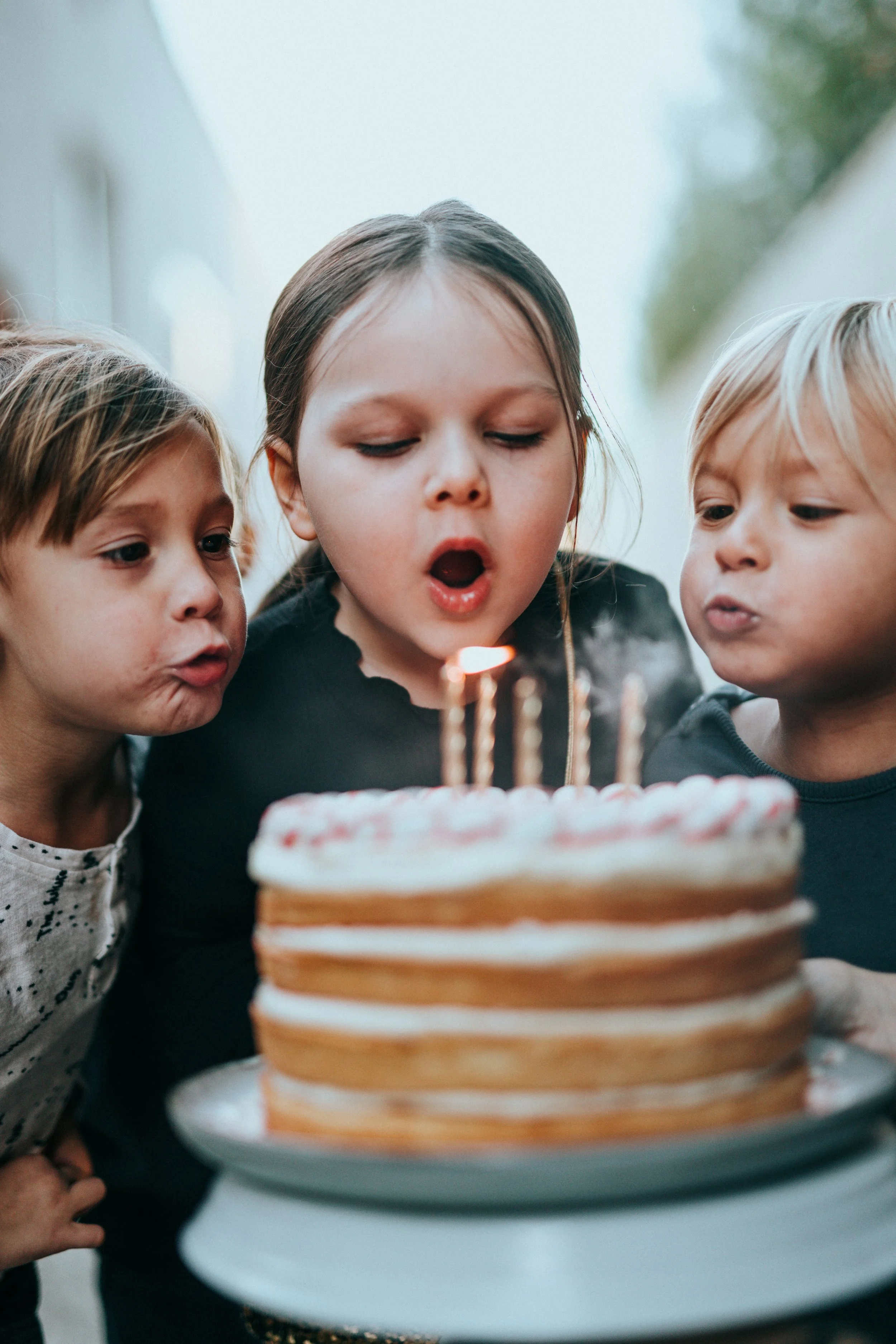 Children blowing out candles on a birthday cake.