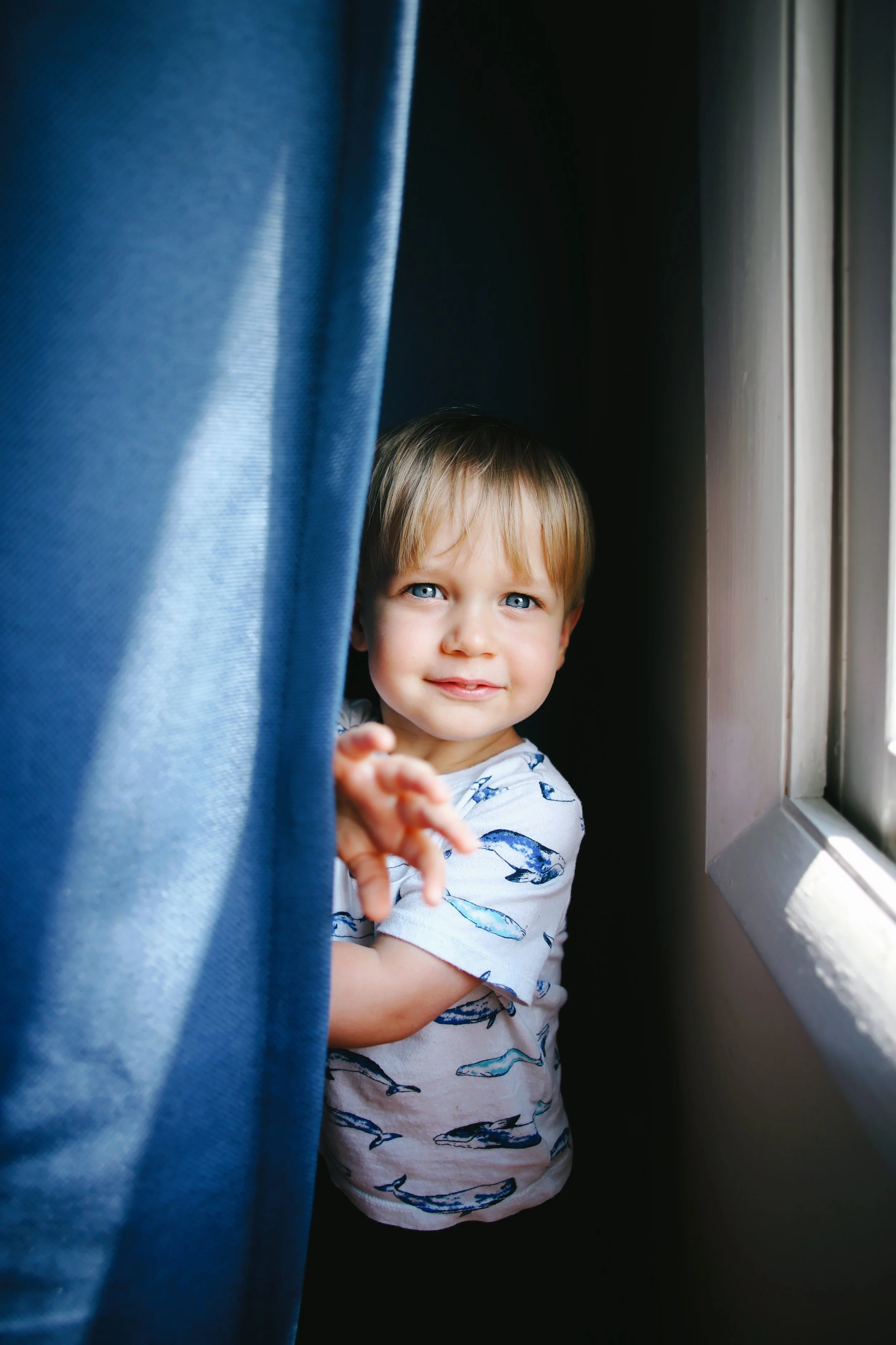 Child peeking from behind a curtain