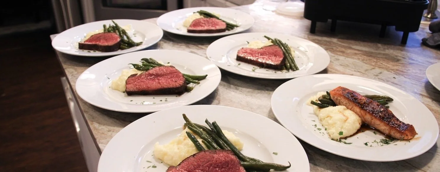 Private chef bachelor party dinner featuring perfectly cooked tri-tip steak, salmon, mashed potatoes, and green beans in a Denver Airbnb.