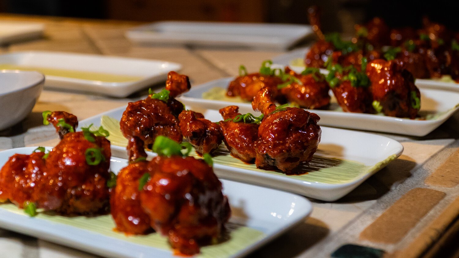 Sticky glazed chicken lollipops garnished with scallions – a crowd-favorite appetizer served at bachelor and bachelorette parties by Dine with Roilty in Denver