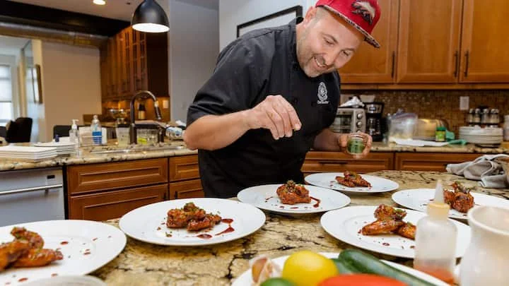 Chef Roilty garnishing plated dishes in a home kitchen