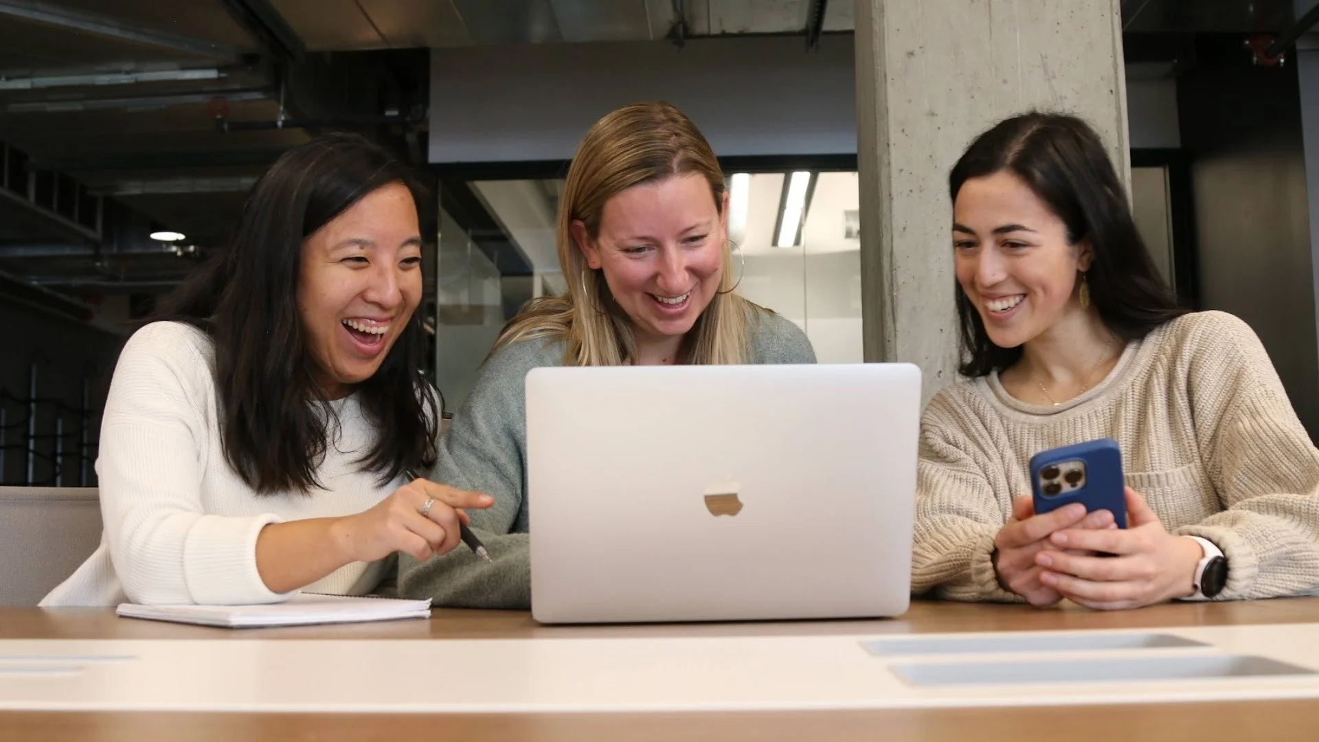Three team members at the Purpose Collective smiling while working together on a laptop
