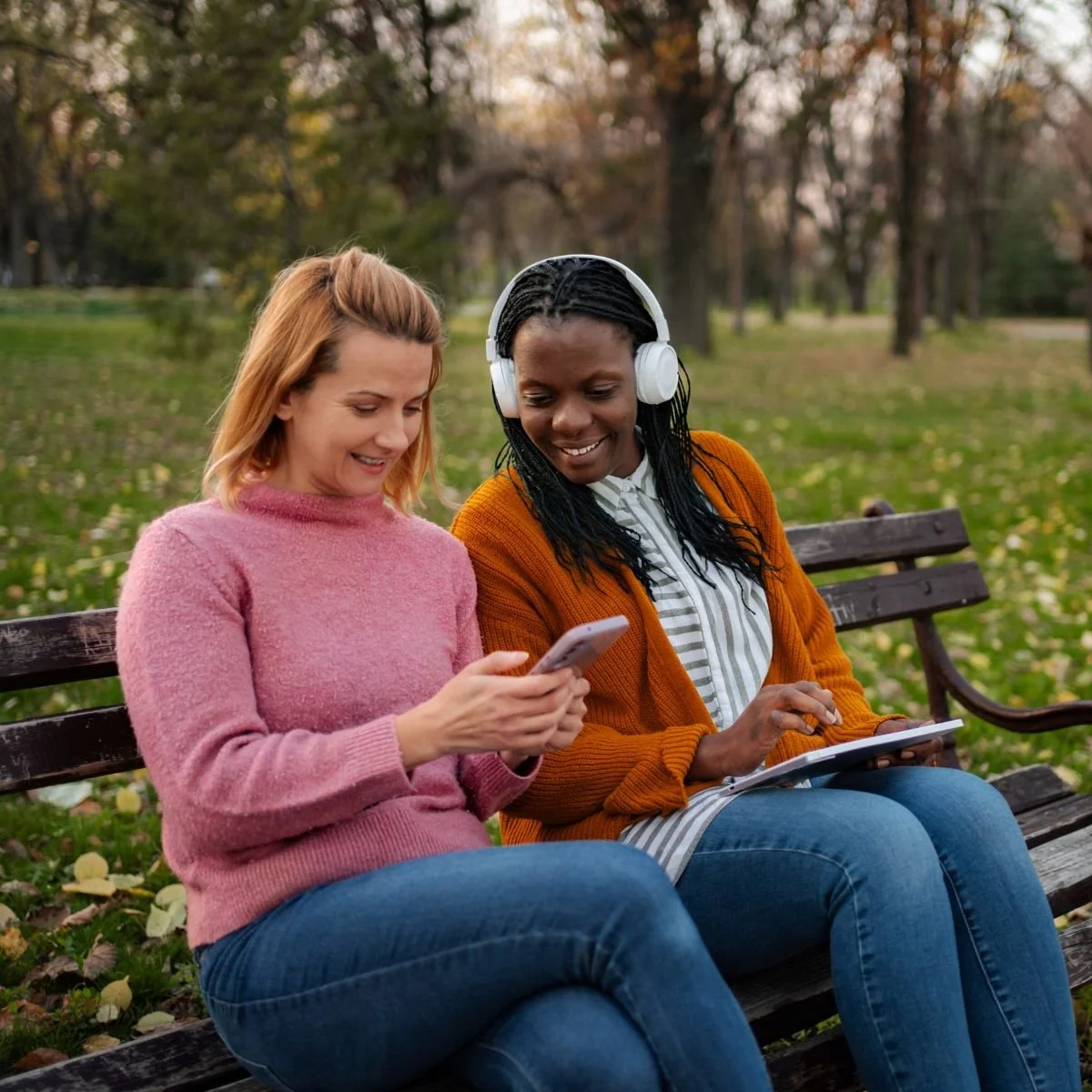 Two friends sitting in a park looking at a nonprofit's digital content