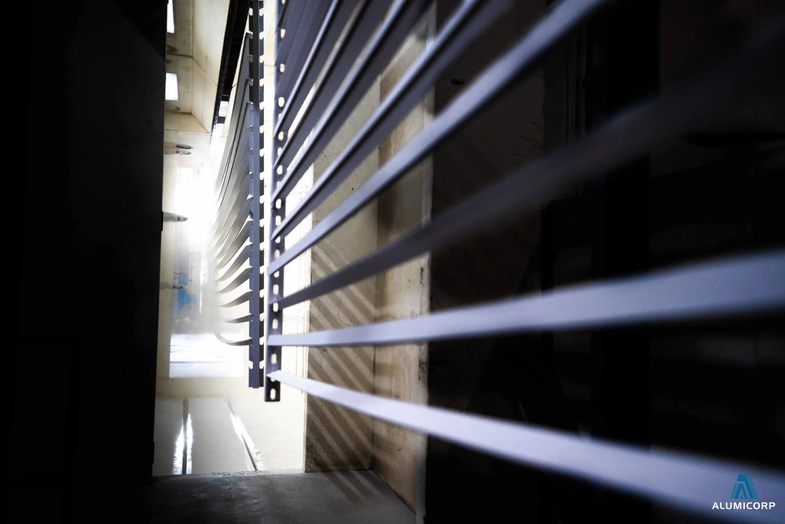 View through horizontal metal bars at a bright hallway with a closed door and blue paint on the wall, seen from below.