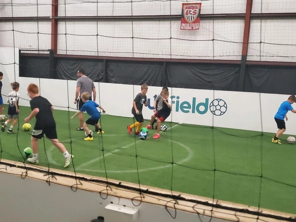 pre-teens practice soccer skills on indoor field