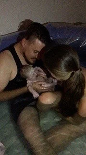 A couple in a water birthing tub, holding a newborn baby. A waterbirth aided by sierra madre midwifery, kaylise jones, and kattie jones.