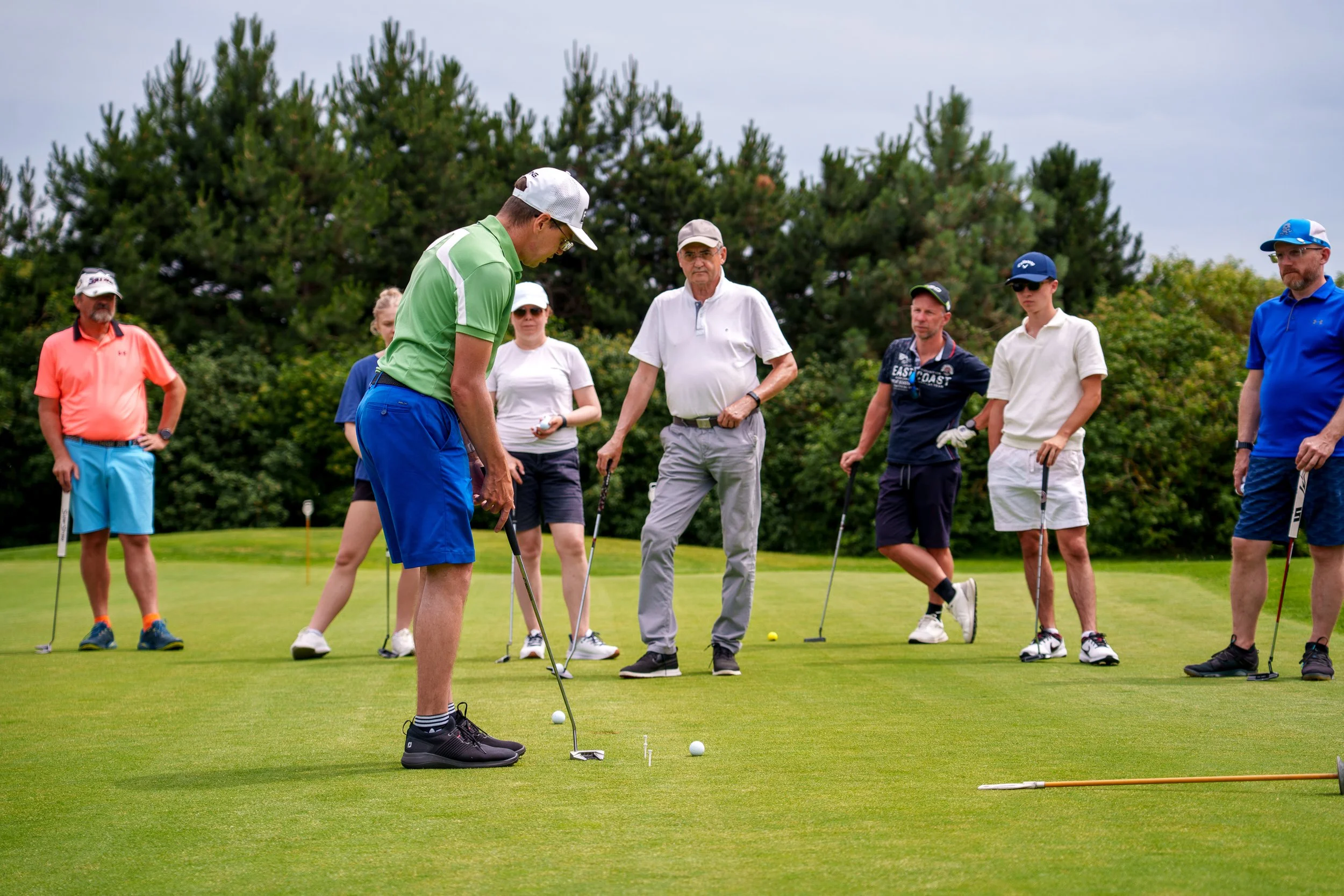 trener golfa uczy grupę początkujących golfistów