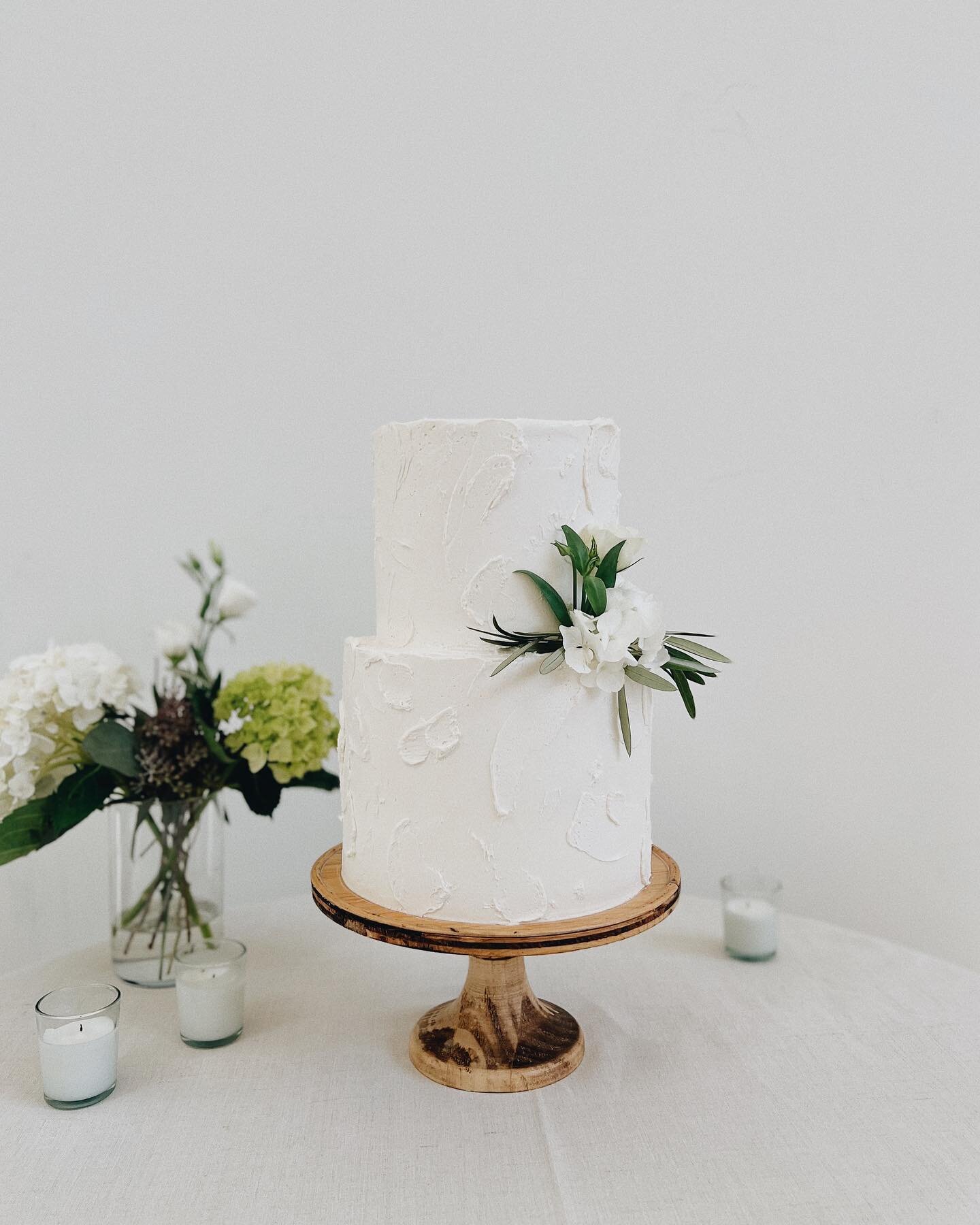 a simple textured two tiered cake with some minimal fresh floral 

flavors: coconut cake and chocolate bourbon cake, all with vanilla buttercream (&amp; some mini chocolate chip sea salt cookies for a milk &amp; cookies shot!) 🍪