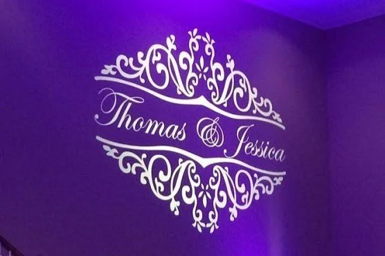 Decorative wall decal with the names Thomas and Jessica on a purple wall.