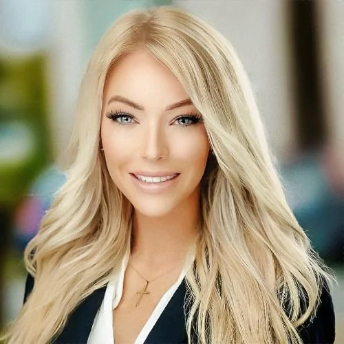 Portrait of a smiling woman wearing a black blazer and gold cross necklace.