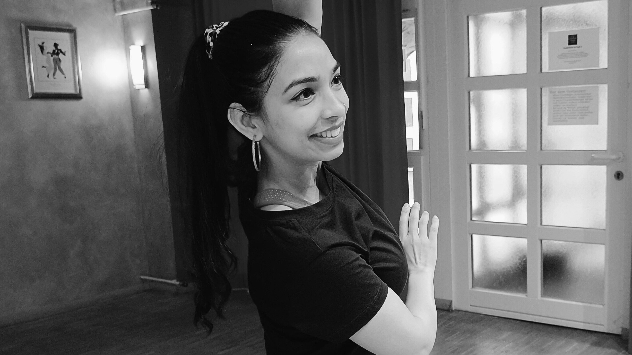 tanzende Frau in einem Raum mit Vorhang im Hintergrund und einer Tür.