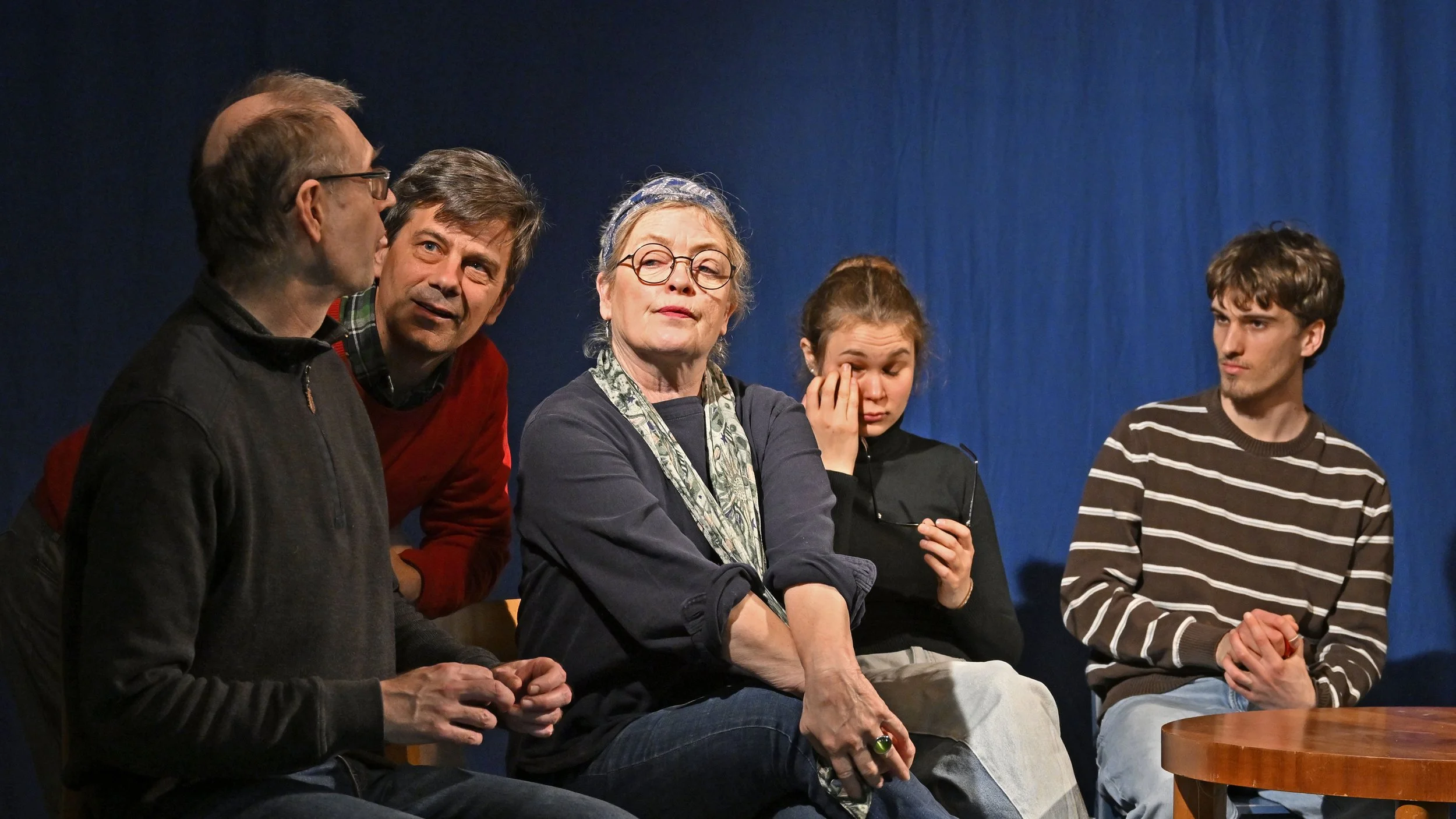 Foto mit 5 Personen im Halbkreis und einem Tisch