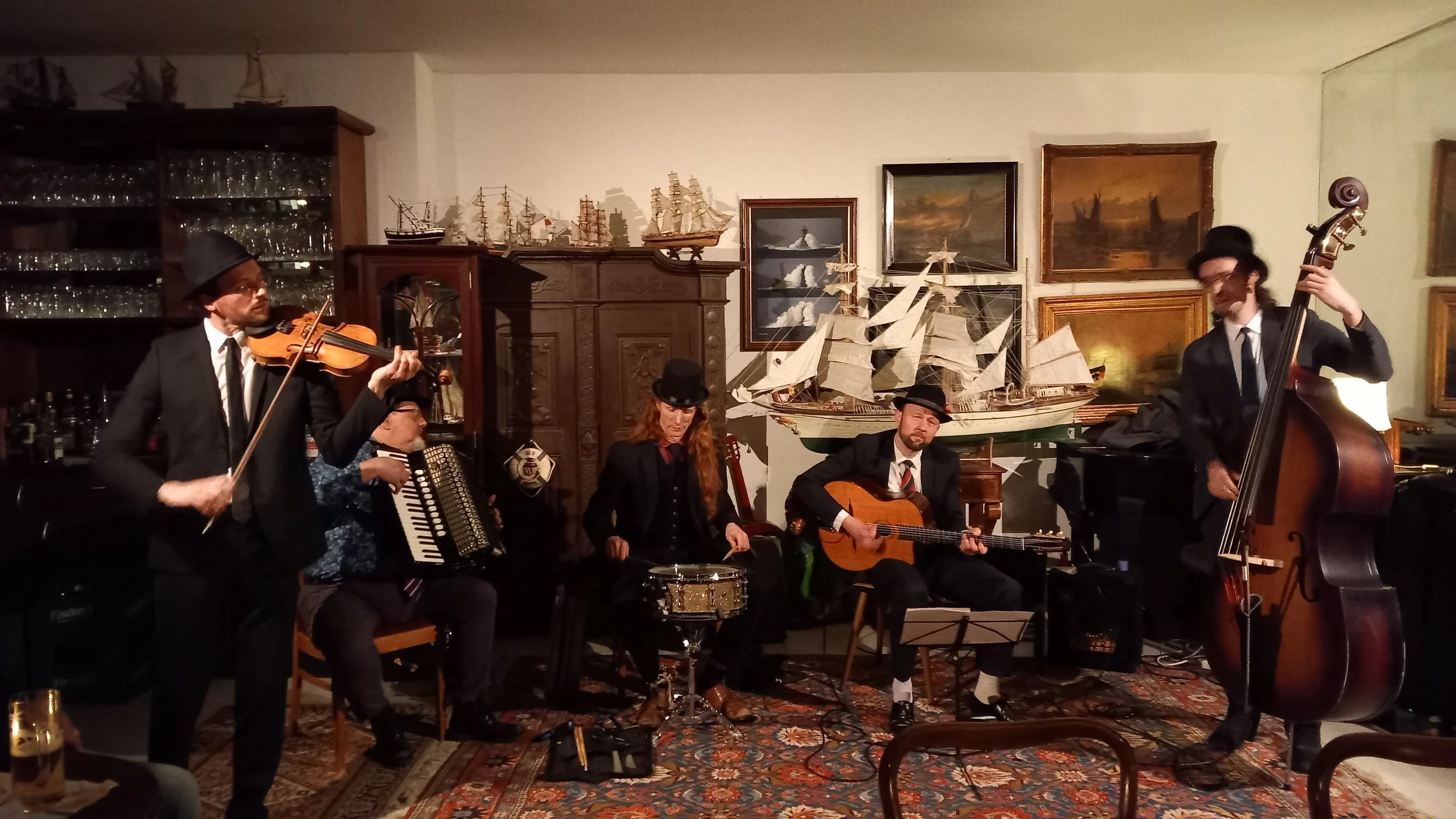 Mehrere Musiker in einem Wohnzimmer mit viel Dekoration im Hintergrund