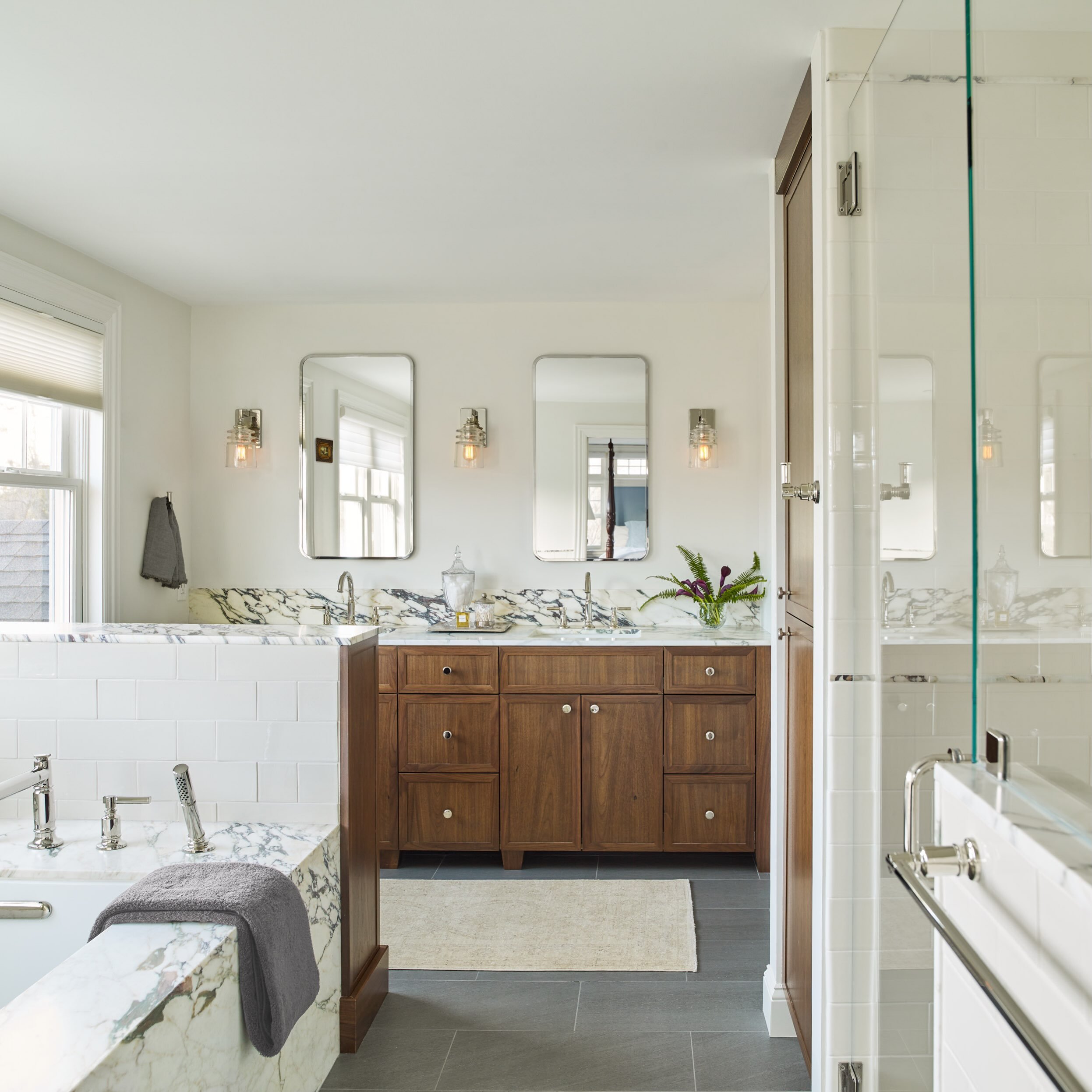 A thoughtful mix of natural materials creates a space that feels warm, layered and timeless. 

In this Primary Bathroom the richness of the custom walnut cabinetry brings depth and warmth while the veining of calacatta viola marble adds movement and 