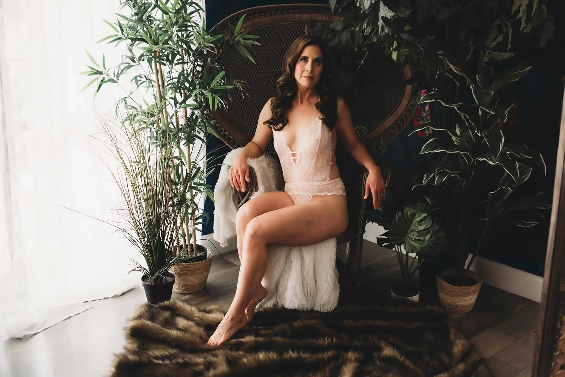 Woman in white lingerie seated in a rattan chair surrounded by plants in a Tampa studio